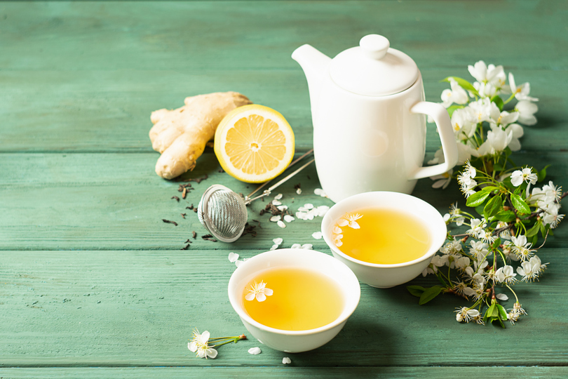 Čaj od limunovog đumbira sa medom u beloj šoljici i čajnik na drvenoj rustikalnoj pozadini. Zdrav napitak za detoksikaciju zdravlja.