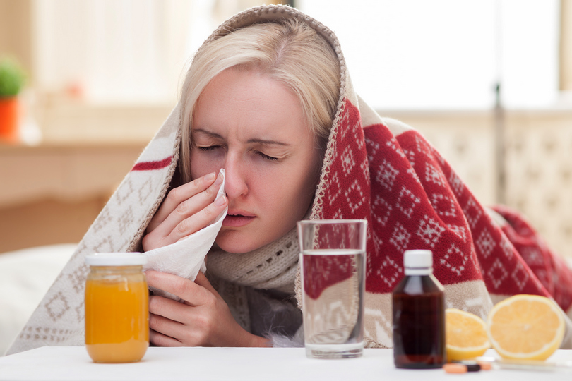 Grip, prehlada, mlada žena duva nos pokrivena ćebetom